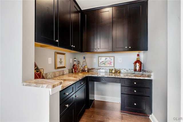 kitchen with dark wood-type flooring, dishwasher, and light stone counters