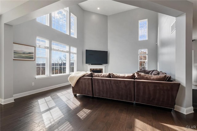 living room with a towering ceiling, dark hardwood / wood-style floors, and plenty of natural light