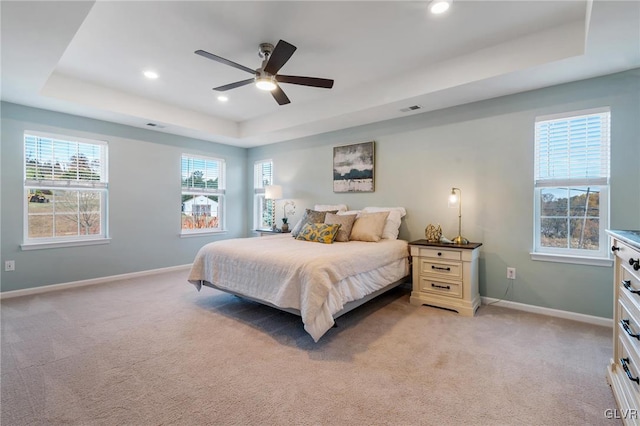 carpeted bedroom featuring ceiling fan and a tray ceiling