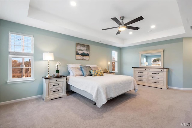 bedroom with a tray ceiling, light carpet, and ceiling fan