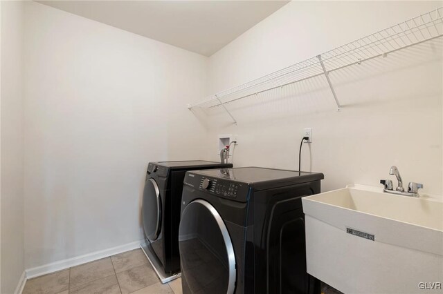 washroom featuring sink, light tile patterned floors, and washing machine and clothes dryer