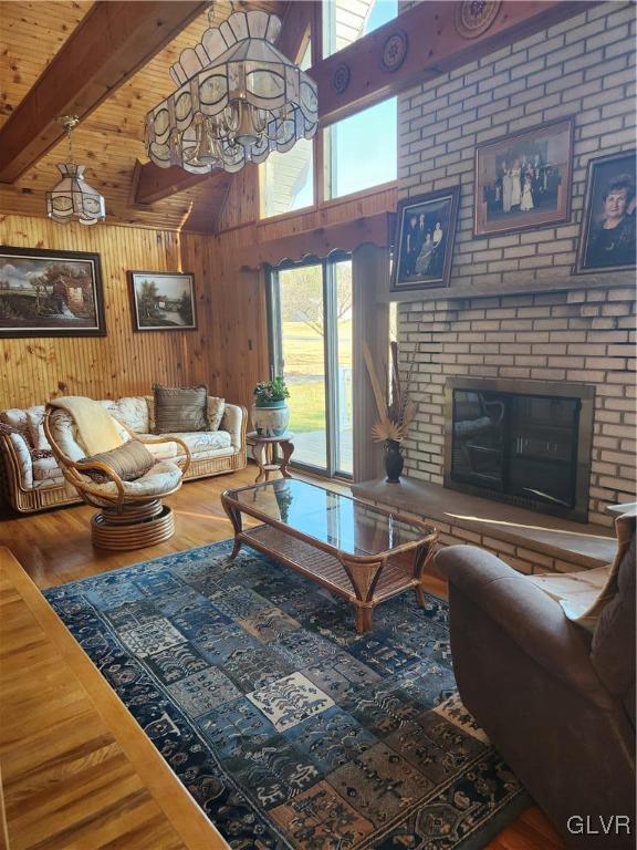 living room featuring beamed ceiling, wood walls, hardwood / wood-style floors, and a brick fireplace