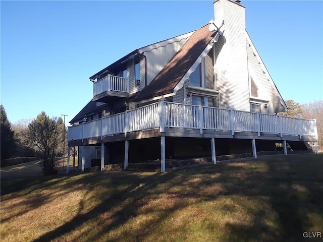 back of property with a deck, a yard, and a balcony