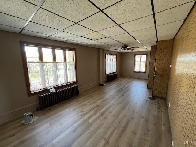 spare room with radiator, a paneled ceiling, wood-type flooring, and ceiling fan