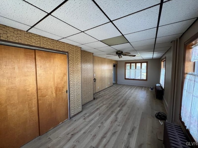 interior space with radiator heating unit, a drop ceiling, and light hardwood / wood-style floors