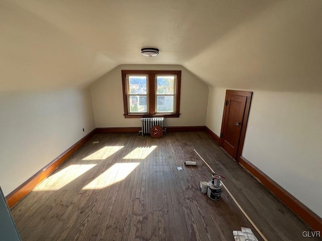 additional living space featuring dark hardwood / wood-style flooring, radiator heating unit, and vaulted ceiling