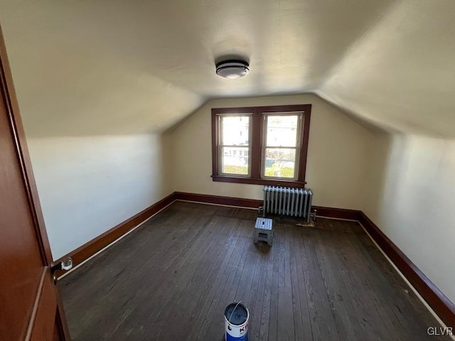 additional living space with radiator, dark hardwood / wood-style floors, and lofted ceiling