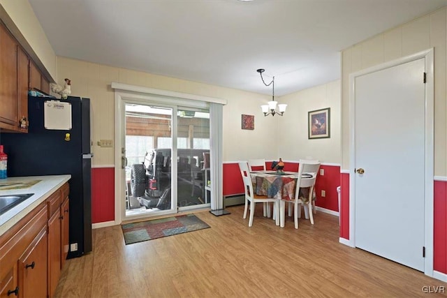 dining space with an inviting chandelier, a baseboard radiator, and light wood-type flooring