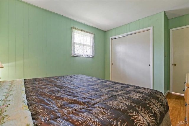 bedroom featuring wood walls, wood-type flooring, and a closet