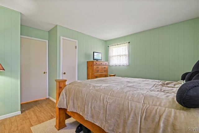 bedroom featuring light wood-type flooring and wooden walls