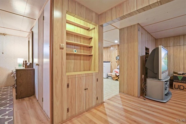 hall with wood walls, light wood-type flooring, and washer / dryer