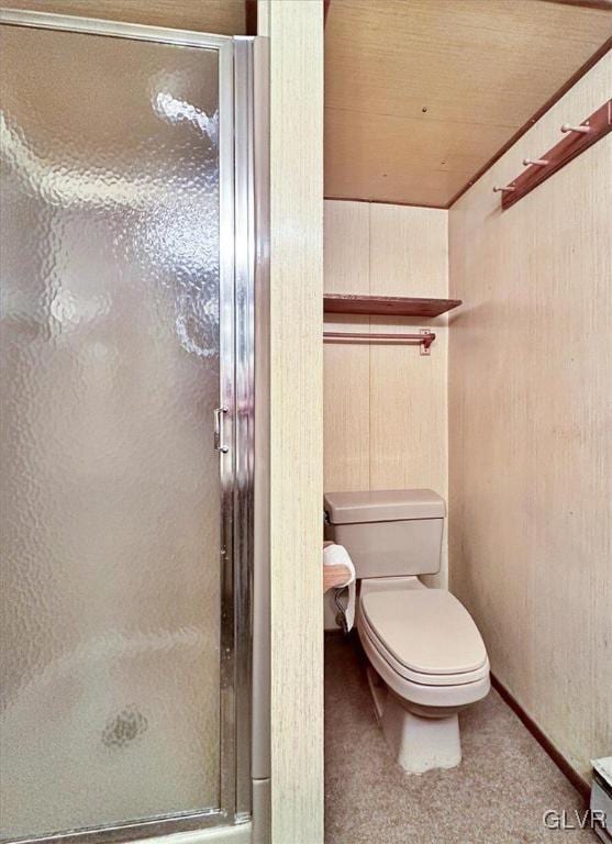 bathroom featuring wood walls, toilet, and a shower with shower door