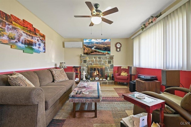 living room with a stone fireplace, a wall mounted air conditioner, and ceiling fan