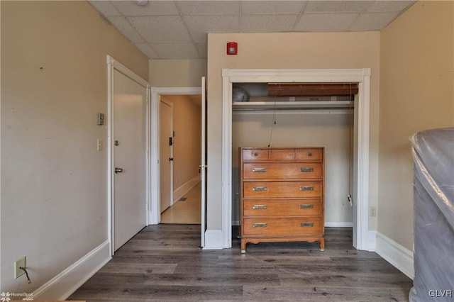 unfurnished bedroom with dark hardwood / wood-style floors, a paneled ceiling, and a closet