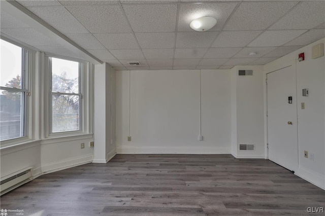 unfurnished room featuring wood-type flooring, a baseboard radiator, and a drop ceiling