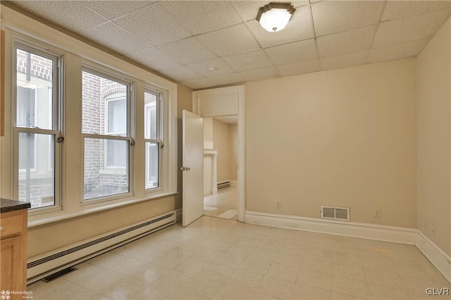 unfurnished room with a drop ceiling and a baseboard radiator