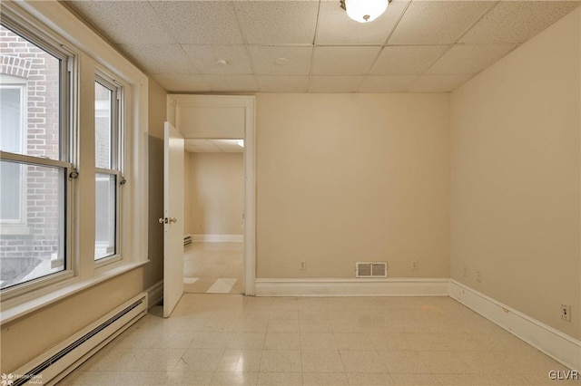 spare room with a paneled ceiling and a baseboard heating unit