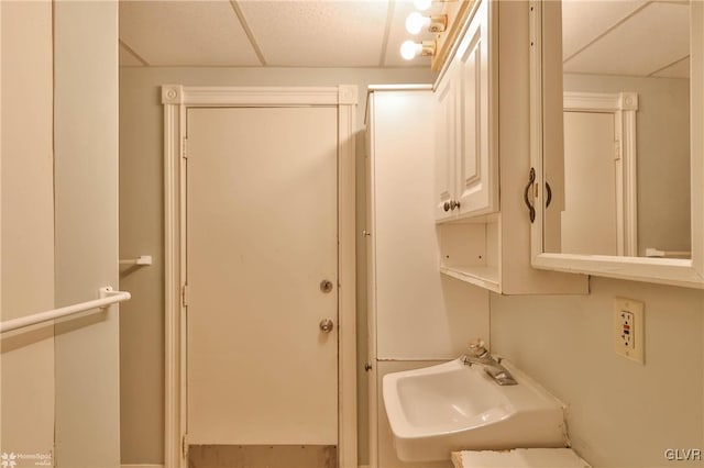 bathroom with a paneled ceiling and sink