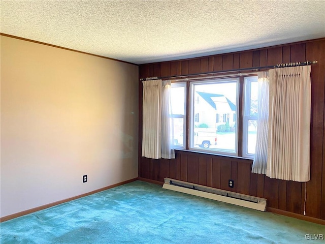 carpeted empty room with wooden walls, a textured ceiling, and a baseboard radiator