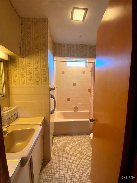 bathroom featuring shower / bath combo with shower curtain, vanity, tile patterned floors, and tile walls