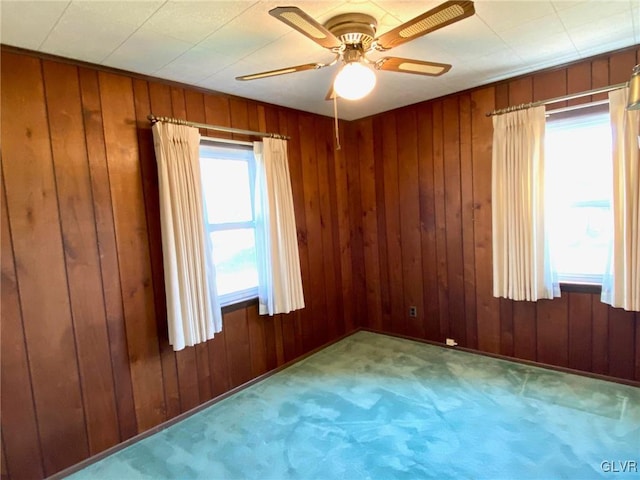 spare room with wood walls, ceiling fan, and carpet floors