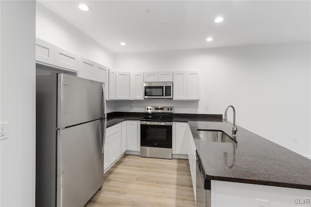 kitchen with recessed lighting, appliances with stainless steel finishes, a sink, light wood-type flooring, and a peninsula