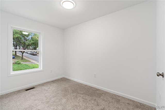 unfurnished room with carpet, visible vents, and baseboards