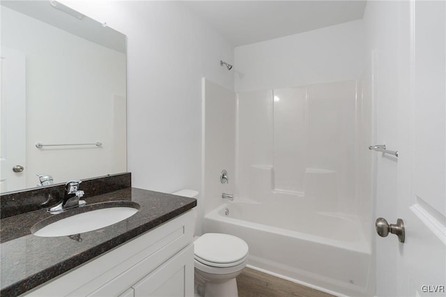 full bathroom featuring washtub / shower combination, hardwood / wood-style flooring, vanity, and toilet