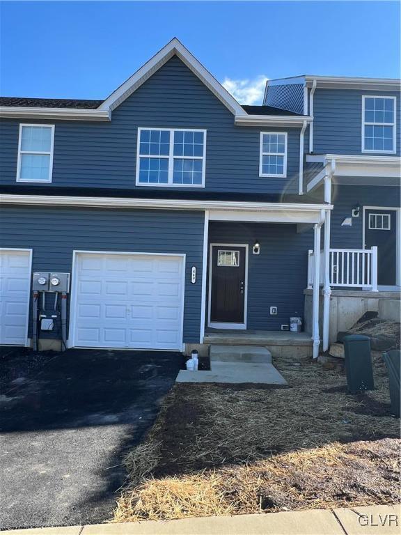 view of front facade featuring driveway, a porch, and an attached garage