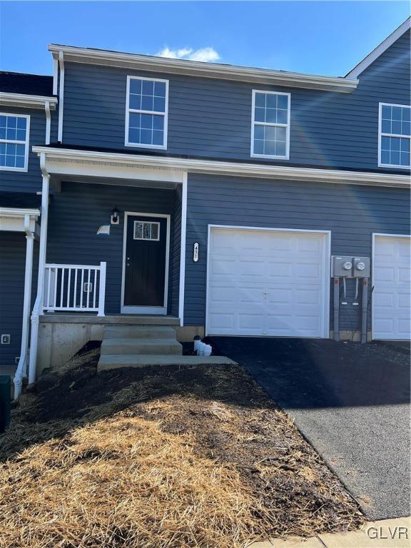 traditional home with covered porch, aphalt driveway, and an attached garage