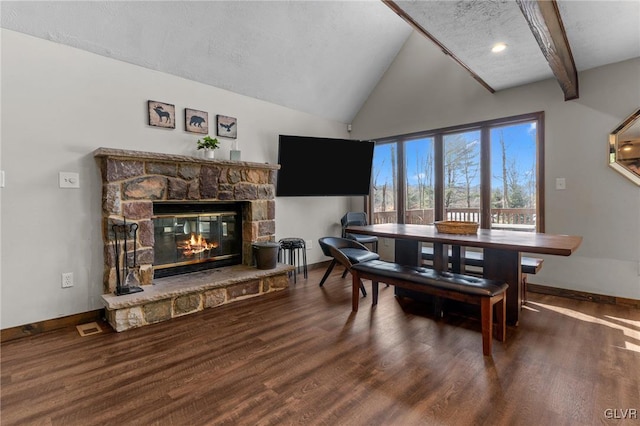 dining room with dark wood-type flooring, vaulted ceiling with beams, and a fireplace