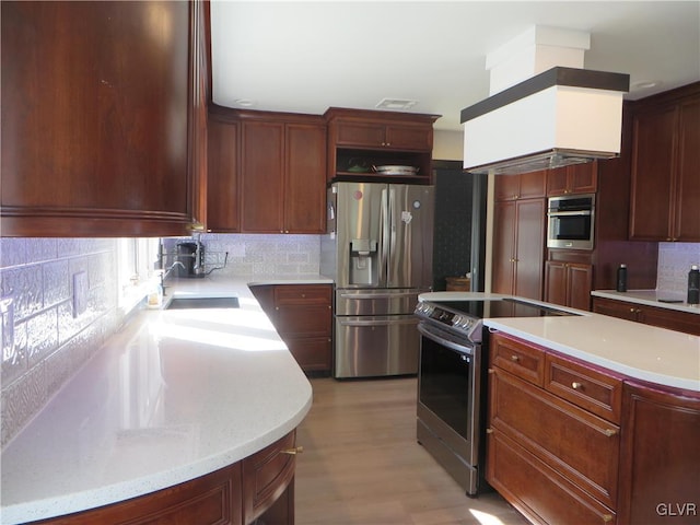 kitchen with stainless steel appliances, sink, backsplash, and light hardwood / wood-style flooring