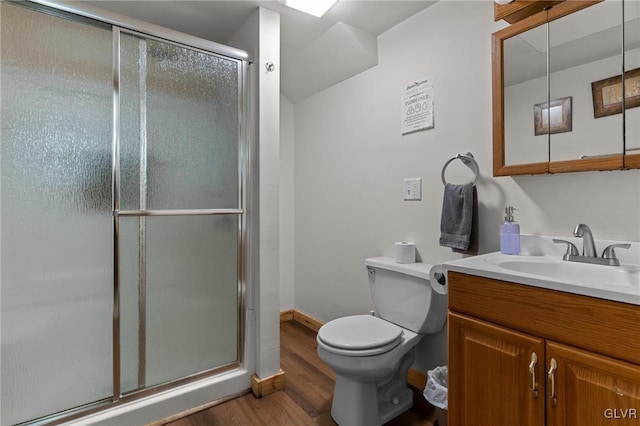 bathroom featuring toilet, a shower with shower door, hardwood / wood-style floors, and vanity