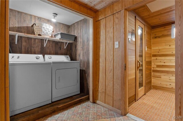 laundry area featuring wood walls and separate washer and dryer