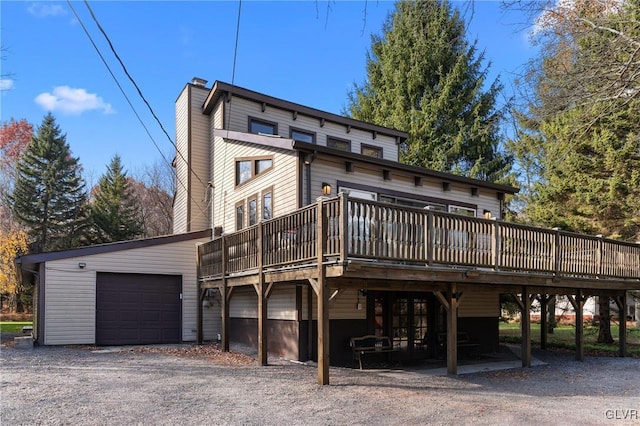 rear view of property featuring a garage and a wooden deck