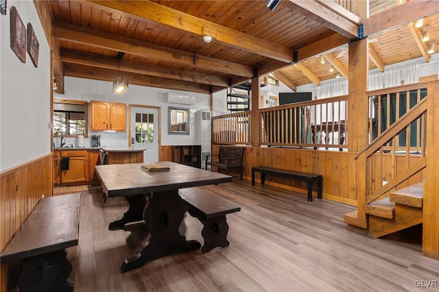 dining space featuring wooden ceiling, a wall mounted air conditioner, track lighting, beam ceiling, and light hardwood / wood-style flooring