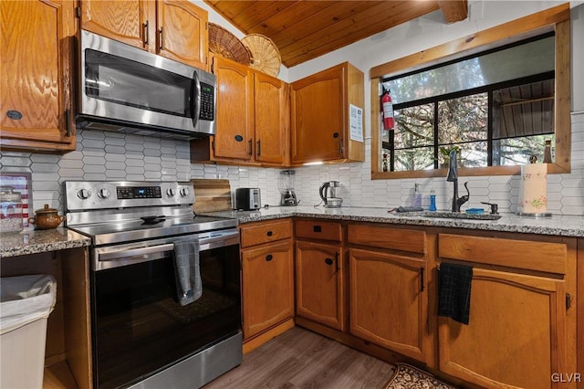 kitchen featuring wooden ceiling, appliances with stainless steel finishes, dark wood-type flooring, vaulted ceiling, and light stone counters