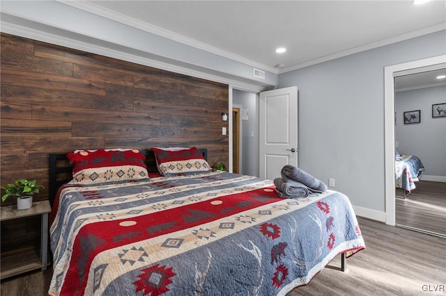 bedroom featuring wood-type flooring, wooden walls, and ornamental molding