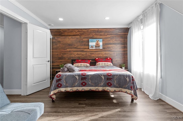 bedroom featuring crown molding, wood-type flooring, and wood walls