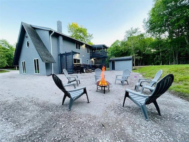 rear view of house with a balcony, a fire pit, and a storage unit