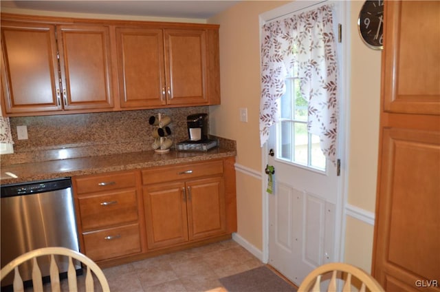 kitchen with dark stone countertops, tasteful backsplash, stainless steel dishwasher, and light tile patterned floors