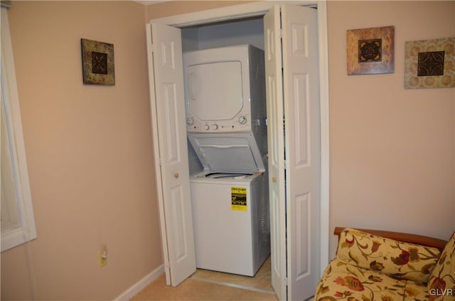 laundry area with baseboards, stacked washer and clothes dryer, and laundry area