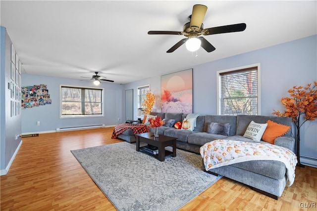 living room featuring hardwood / wood-style floors, ceiling fan, a healthy amount of sunlight, and a baseboard heating unit