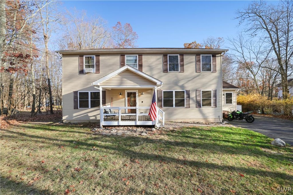 colonial house featuring cooling unit, a front yard, and a deck