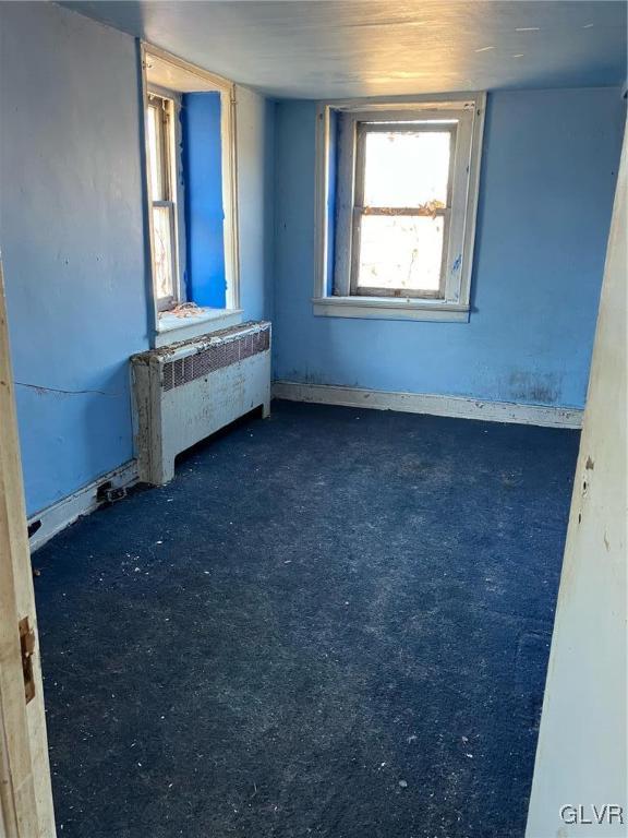 empty room featuring radiator heating unit and dark carpet