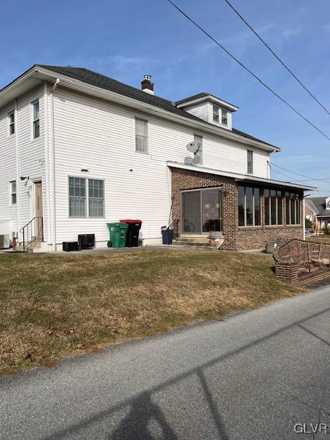 view of side of property with a sunroom, a yard, and cooling unit