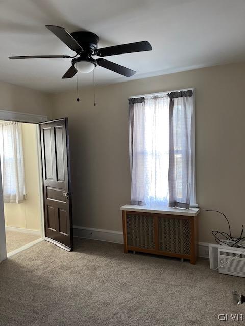 unfurnished bedroom with radiator heating unit, light carpet, multiple windows, and ceiling fan