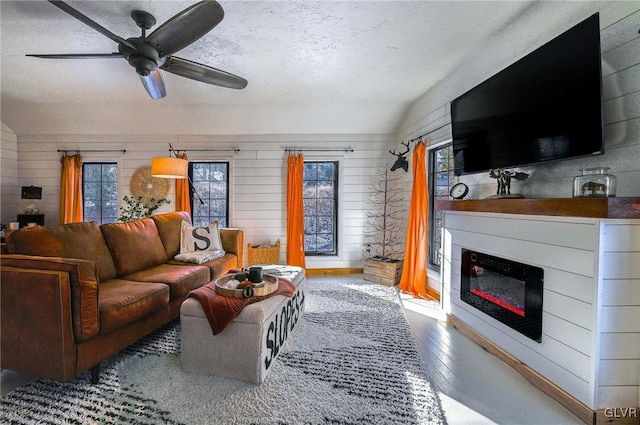 living room featuring vaulted ceiling, wood walls, and light wood-type flooring