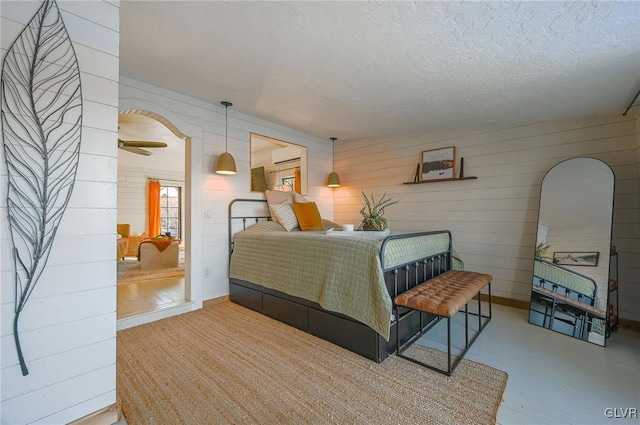 bedroom featuring an AC wall unit, wood walls, and a textured ceiling