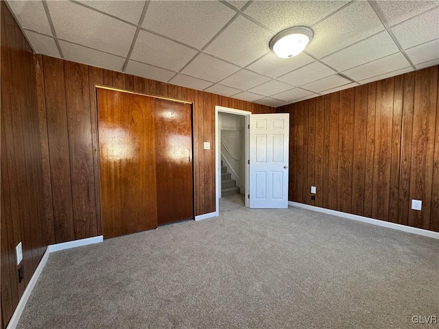 unfurnished bedroom with wood walls, a paneled ceiling, and a closet